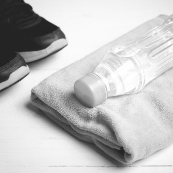 fitness equipment: towel,drinking water and running shoes on white wood table black and white color style