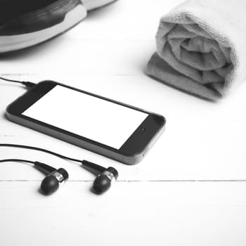 fitness equipment:running shoes,towel and smart phone on white wood table black and white color style