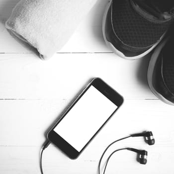 fitness equipment:running shoes,towel and smart phone on white wood table black and white color style