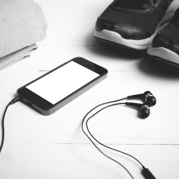 fitness equipment:running shoes,towel and smart phone on white wood table black and white color style