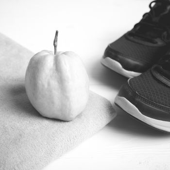 fitness equipment : running shoes,towel and guava fruit on white wood table black and white color style