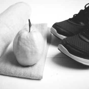 fitness equipment : running shoes,towel and guava fruit on white wood table black and white color style