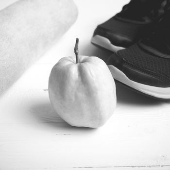 fitness equipment : running shoes,towel and guava fruit on white wood table black and white color style