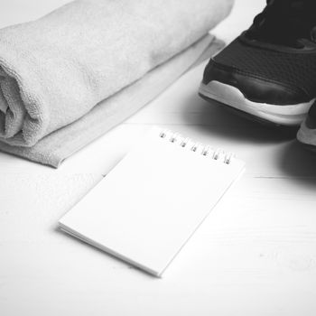 fitness equipment : running shoes,towel and notepad on white wood table black and white color style