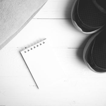 fitness equipment : running shoes,towel and notepad on white wood table black and white color style