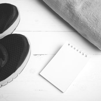 fitness equipment : running shoes,towel and notepad on white wood table black and white color style