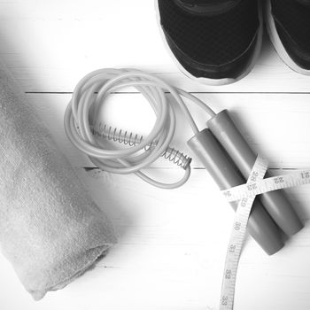 fitness equipment : running shoes,towel,jumping rope and measuring tape on white wood table black and white color tone style