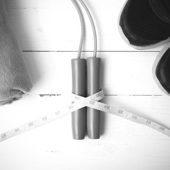 fitness equipment : running shoes,towel,jumping rope and measuring tape on white wood table black and white color tone style