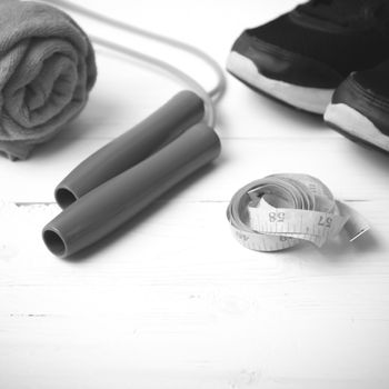 fitness equipment : running shoes,towel,jumping rope and measuring tape on white wood table black and white color tone style