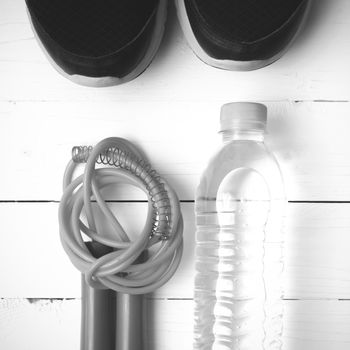 fitness equipment : running shoes,jumping rope and water bottle on white wood table black and white color tone style