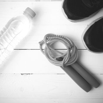 fitness equipment : running shoes,jumping rope and water bottle on white wood table black and white color tone style