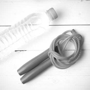 fitness equipment :jumping rope and water bottle on white wood table black and white color tone style