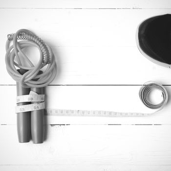 fitness equipment : running shoes,jumping rope and measuring tape on white wood table black and white color tone style