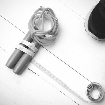 fitness equipment : running shoes,jumping rope and measuring tape on white wood table black and white color tone style