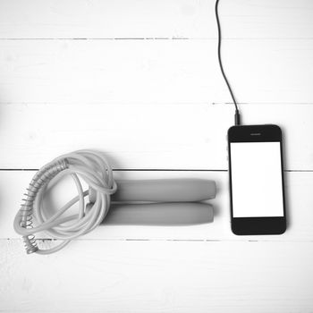 fitness equipment : jumping rope and phone on white wood table black and white color tone style