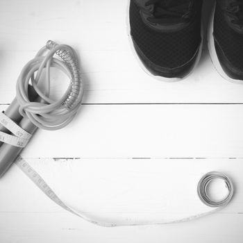 fitness equipment : running shoes,jumping rope and measuring tape  on white wood table black and white color tone style