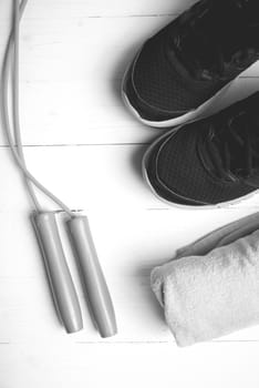 fitness equipment: towel,jumping rope and running shoes on white wood table black and white color style