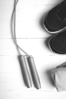 fitness equipment: towel,jumping rope and running shoes on white wood table black and white color style