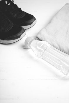 fitness equipment: towel,drinking water and running shoes on white wood table black and white color style