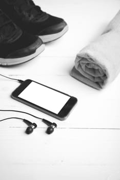 fitness equipment:running shoes,towel and smart phone on white wood table black and white color style