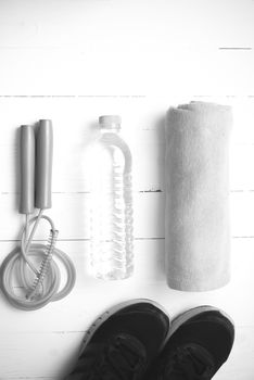 fitness equipment : running shoes,towel,jumping rope and drinking water on white wood table black and white color tone style