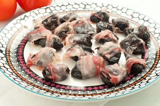 Prunes wrapped in bacon and baked, italy