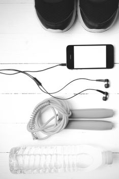 fitness equipment : running shoes,jumping rope,phone and water bottle on white wood table