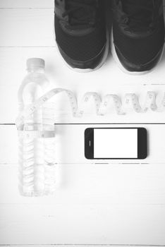 fitness equipment : running shoes,drinking water,measuring tape and phone on white wood table black and white tone color style