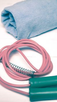 fitness equipment:blue towel,jumping rope on white wood table vintage style