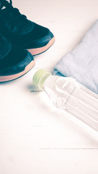 fitness equipment:blue towel,drinking water and running shoes on white wood table vintage style