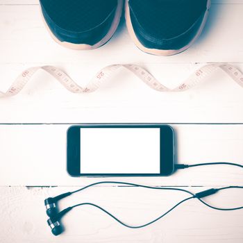 running shoes,measuring tape and phone on white wood table vintage style