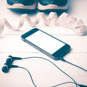 running shoes,measuring tape and phone on white wood table vintage style