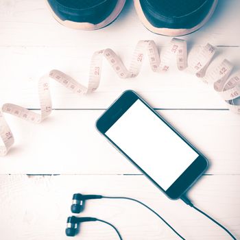 running shoes,measuring tape and phone on white wood table vintage style