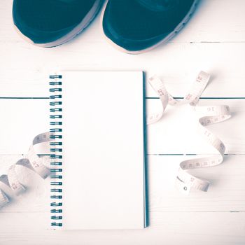 running shoes with notebook and measuring tape on white wood table vintage style