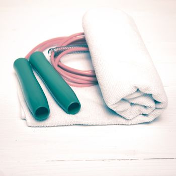 fitness equipment:white towel,jumping rope on white wood table vintage style