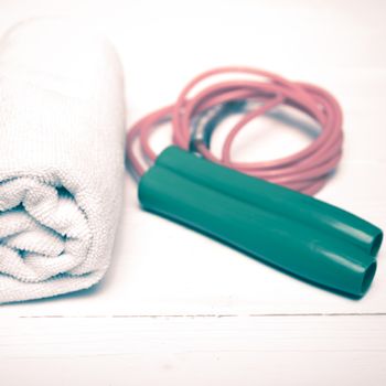 fitness equipment:white towel,jumping rope on white wood table vintage style