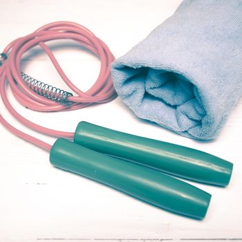 fitness equipment:blue towel,jumping rope on white wood table vintage style