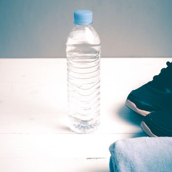 fitness equipment:blue towel,drinking water and running shoes on white wood table vintage style