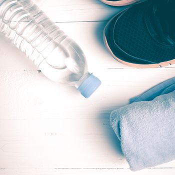 fitness equipment:blue towel,drinking water and running shoes on white wood table vintage style