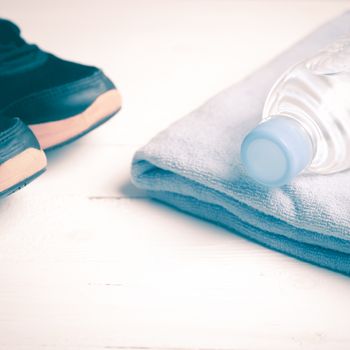 fitness equipment:blue towel,drinking water and running shoes on white wood table vintage style