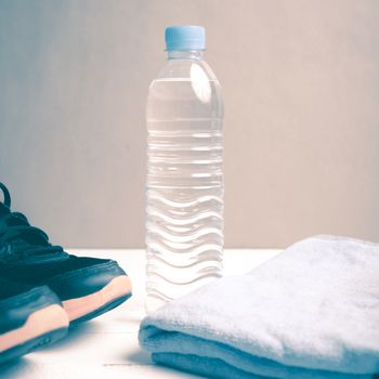 fitness equipment:blue towel,drinking water and running shoes on white wood table vintage style