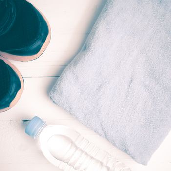 fitness equipment:blue towel,drinking water and running shoes on white wood table vintage style