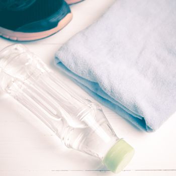 fitness equipment:blue towel,drinking water and running shoes on white wood table vintage style