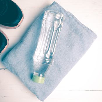 fitness equipment:blue towel,drinking water and running shoes on white wood table vintage style