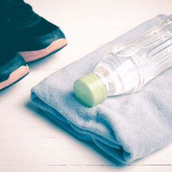 fitness equipment:blue towel,drinking water and running shoes on white wood table vintage style