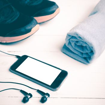 fitness equipment:running shoes,blue towel and smart phone on white wood table vintage style