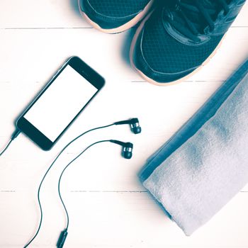 fitness equipment:running shoes,blue towel and smart phone on white wood table vintage style