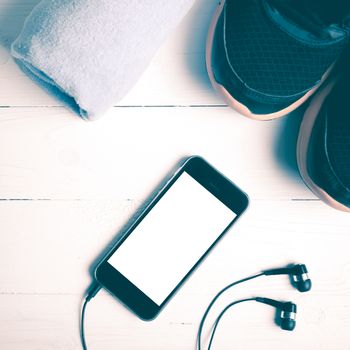 fitness equipment:running shoes,blue towel and smart phone on white wood table vintage style