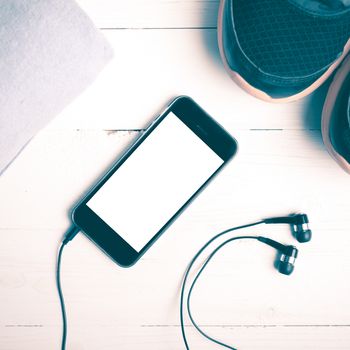 fitness equipment:running shoes,blue towel and smart phone on white wood table vintage style