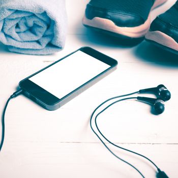fitness equipment:running shoes,blue towel and smart phone on white wood table vintage style